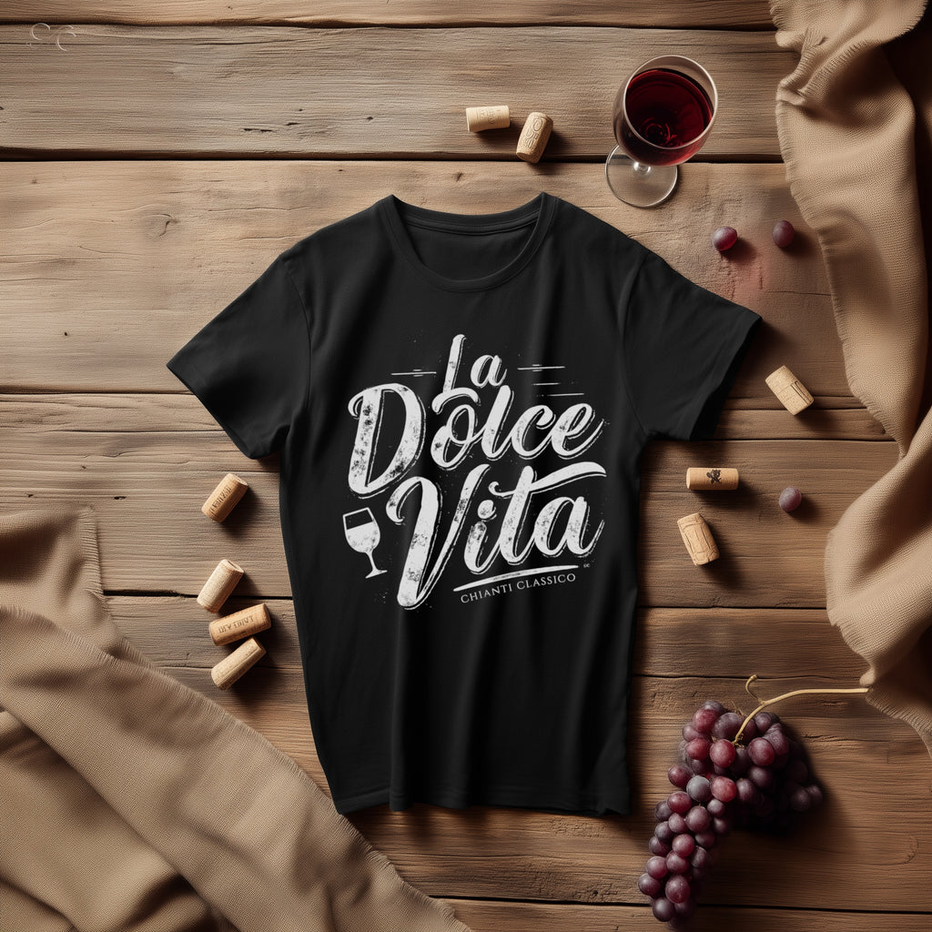 Black ‘La Dolce Vita’ Chianti Classico graphic tee styled on rustic wooden surface with wine corks, glass of red wine, grapes, and burlap cloth.